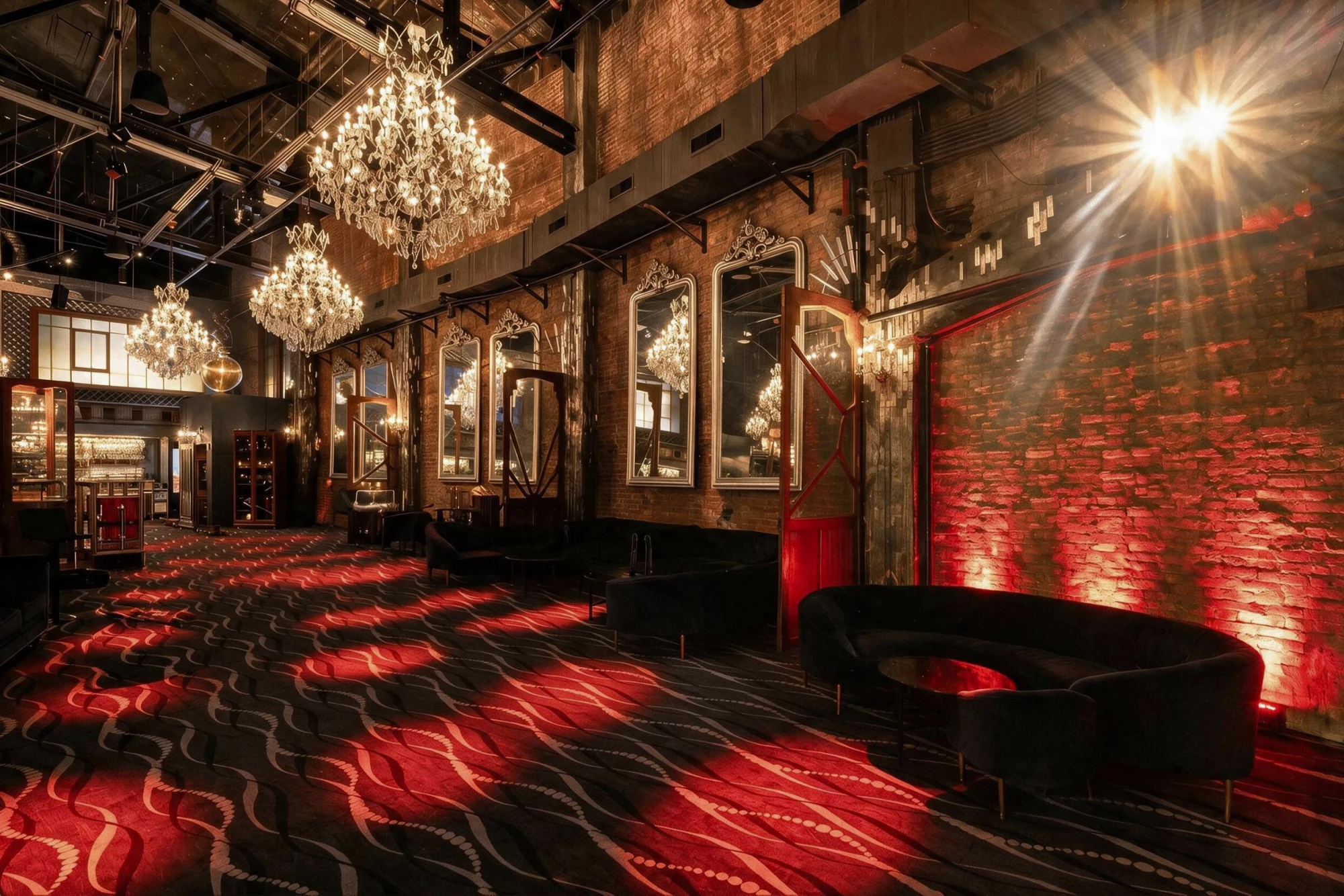 Lounge hall with crystal chandeliers, brick walls, ornate mirrors, velvet sofas, and a wavy carpet