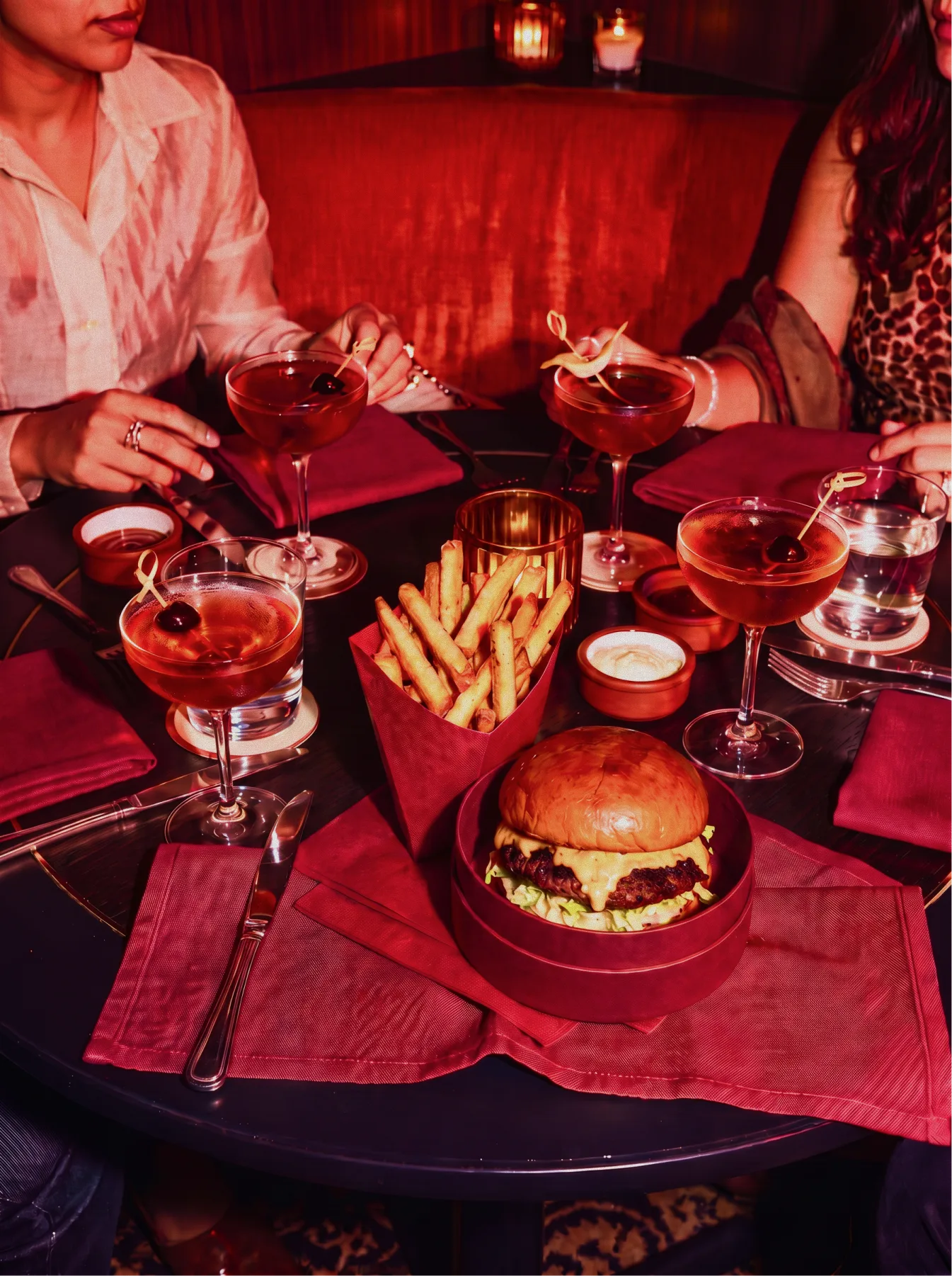 Burger, fries, and cocktails served at a candlelit table